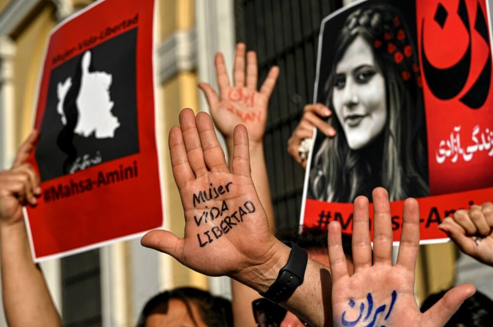 "Woman, life, freedom," demonstrators at a solidarity rally in the Chilean capital Santiago parade the catchcry of the Iran protests on the palms of their hands in Spanish and Persian