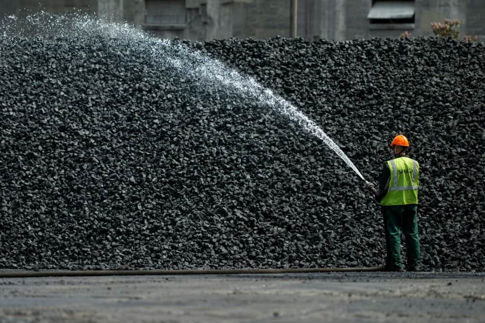 A worker sprays a coal heap with water in Gdansk, Poland to dampen down the dust