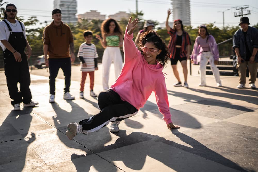 Young woman breakdancing during street party with her friends outdoors.