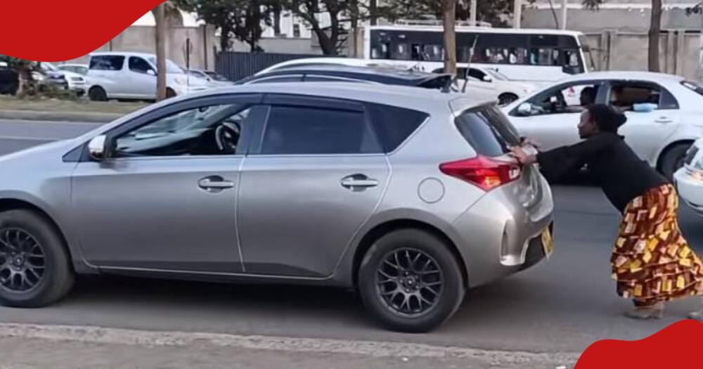 Nairobi woman pushing a car on a busy road.