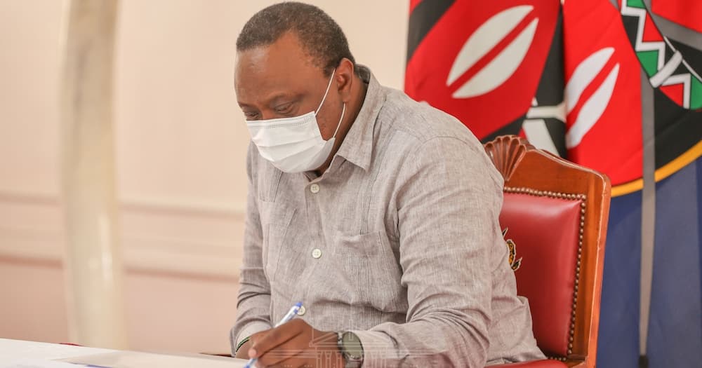 President Uhuru Kenyatta signing a document at his office.