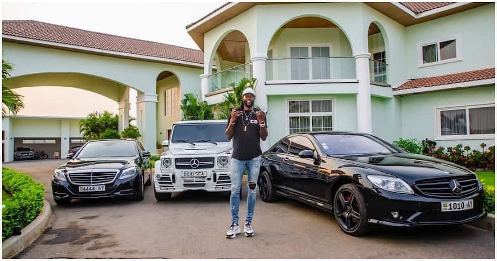 Emmanuel Adebayor poses in front of his house