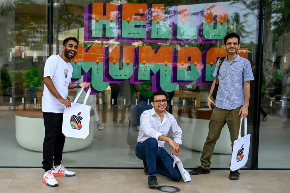 Apple fans pose outside the company's new Mumbai store during a media preview