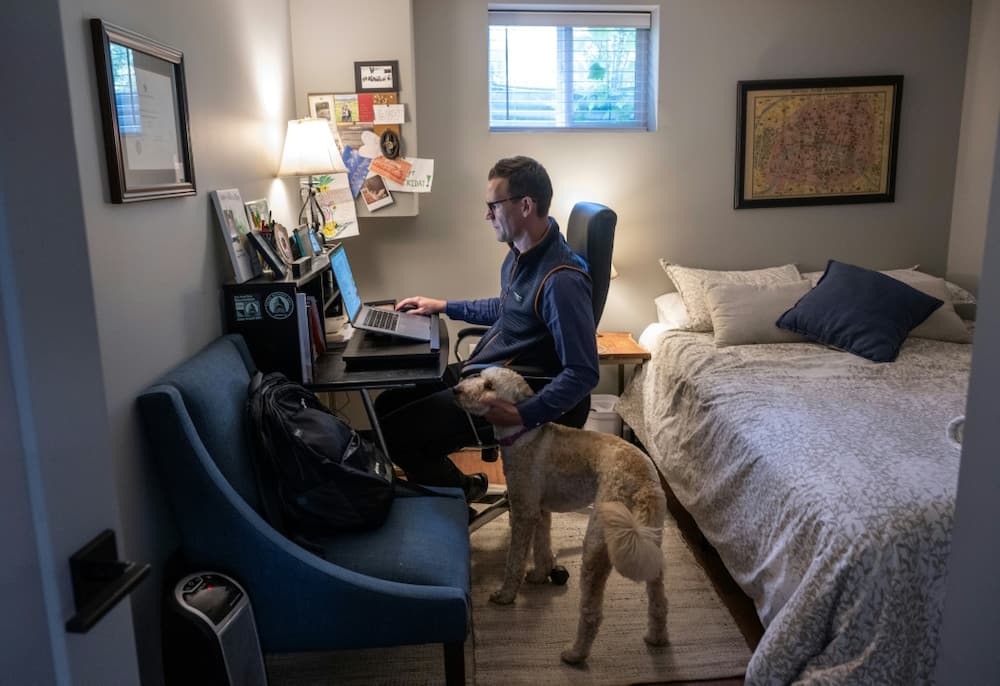 Danny Crouch pets his dog as he sits in his basement working from home in Arlington, Virginia