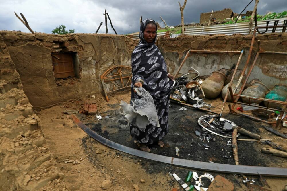 A Sudanese lady stands inside the wreckage of her home torched during clashes in Blue Nile state