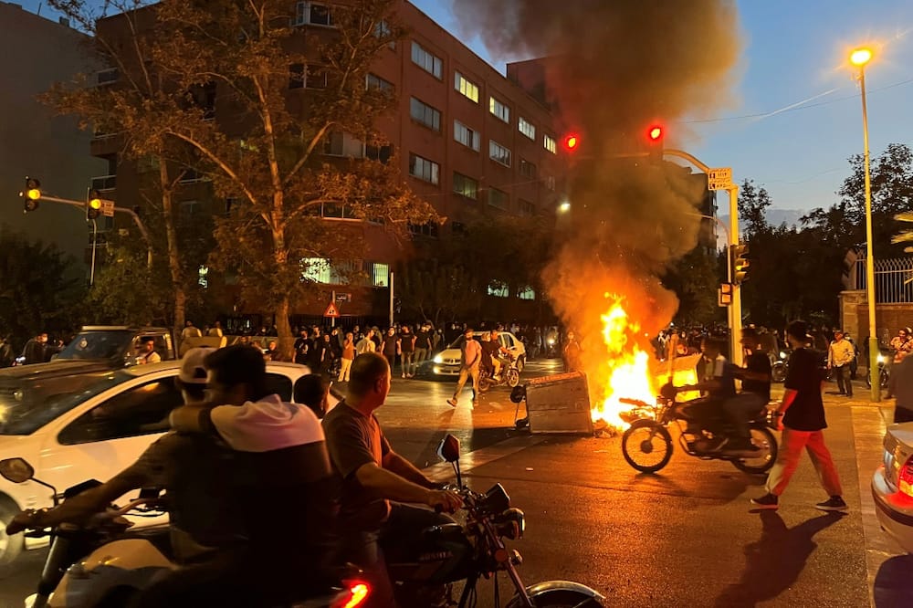A picture obtained by AFP outside Iran shows demonstrators gathering around a burning barricade during a protest in Tehran on September 19, 2022