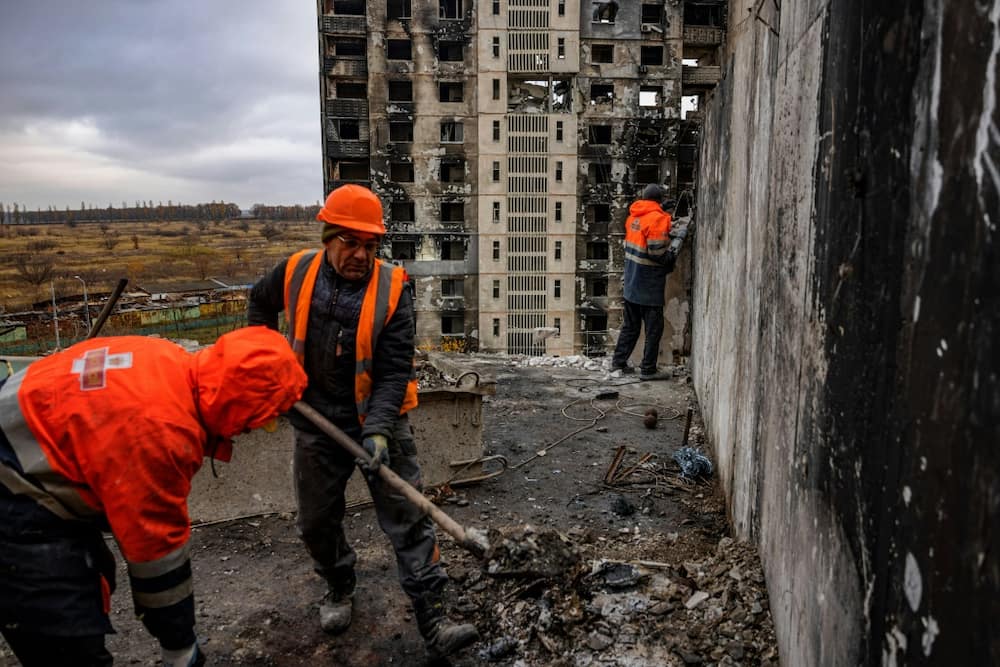Ukraine workers clean debris from a partially destroyed residential building after shelling on the outskirts of Kharkiv