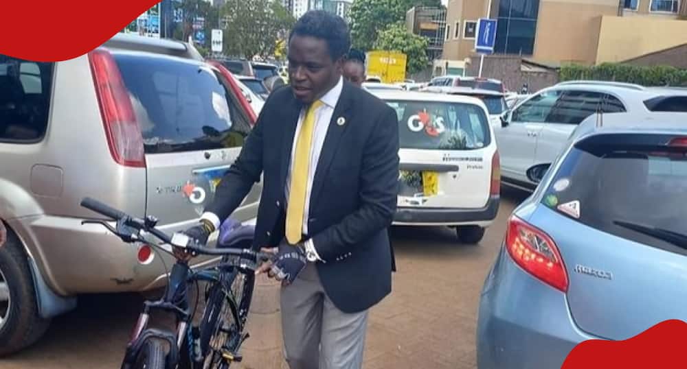 Nelson Havi is pushing his bicycle.