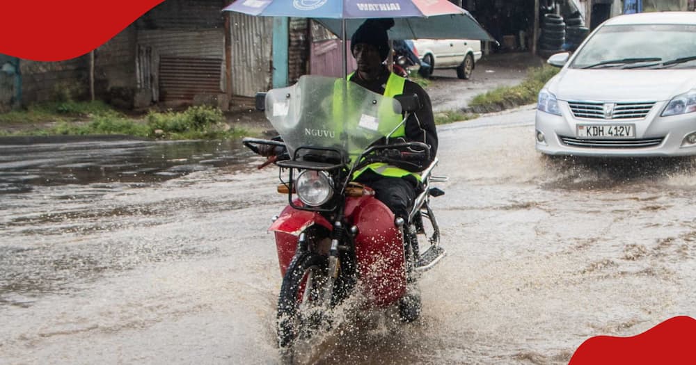 A boda boda taxi rides past a flooded section of a road.
