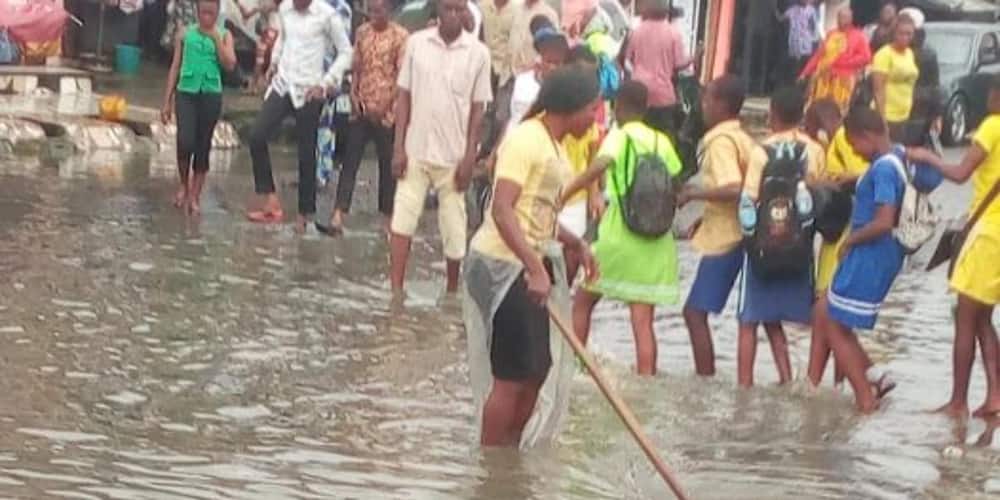 Nigerian Lady Goes Under The Rain To Help School Children Cross A Flooded Market
