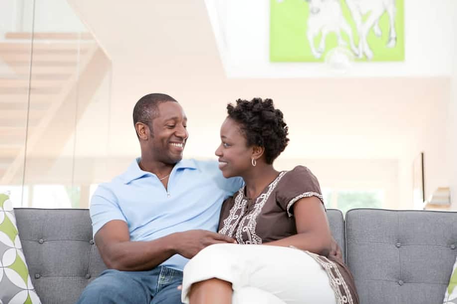 Happy couple sitting on sofa in living room.