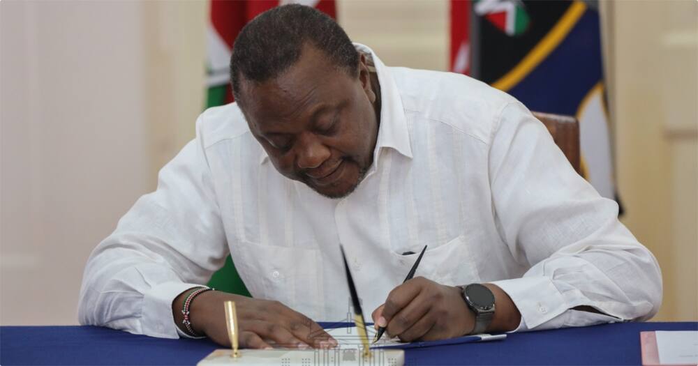 Uhuru signs a document in the past.