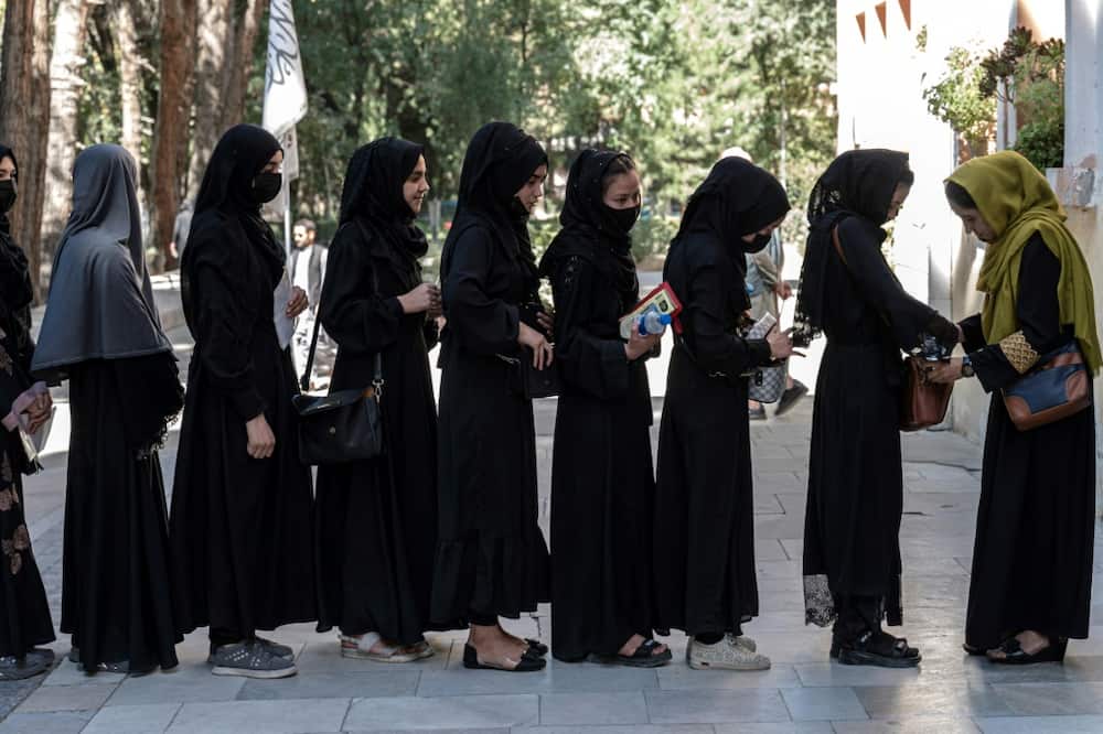 Dressed in black hijabs and headscarves, students queue for their entrance exams outside Kabul University