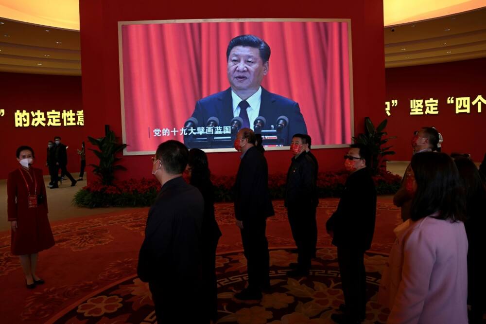 Visitors stand in front of a screen showing Chinese President Xi Jinping during an exhibition at the Beijing Exhibition Center on national achievements