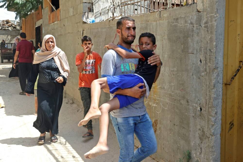 A Palestinian man carries an injured boy following an Israeli air strike, in Khan Yunis in the southern Gaza Strip