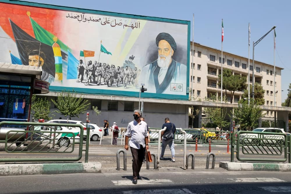 Iranians in Tehran walk past a billboard bearing a portrait of the late supreme leader Ayatollah Ruhollah Khomeini, who in 1989 issued a fatwa calling for author Salman Rushdie to be killed