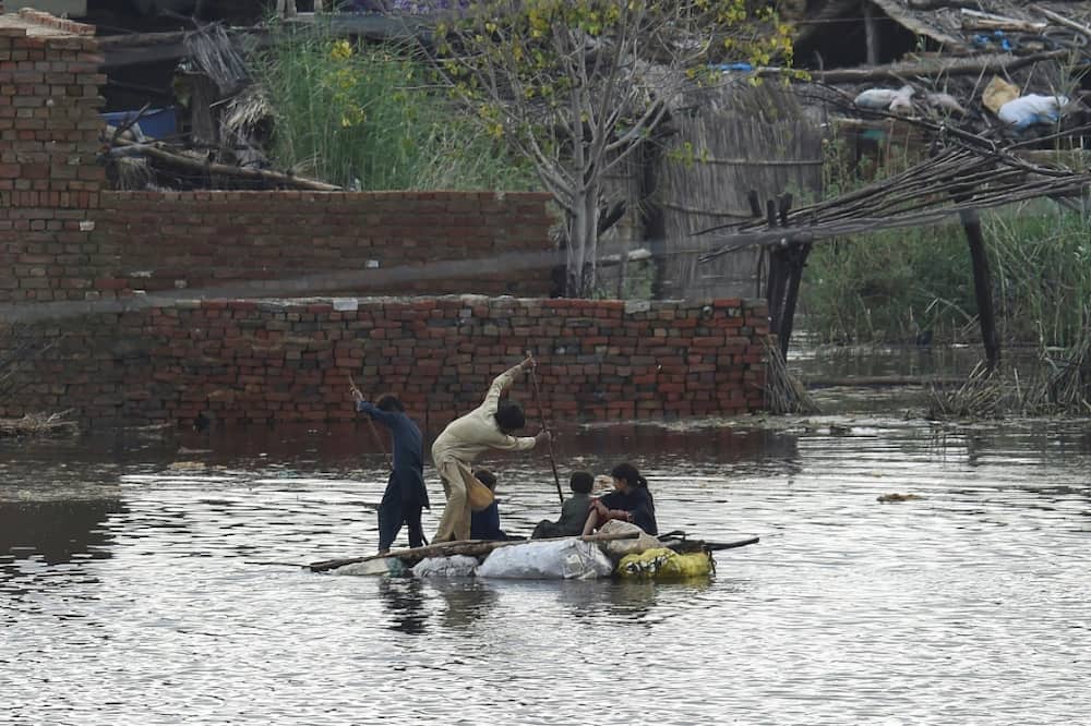 Children use a raft to make their way in a flooded area of Sukkur