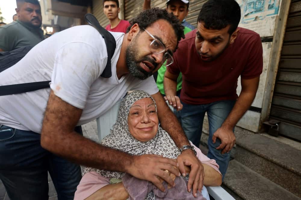 A relative comforts an injured Palestinian woman following an Israeli air strike on Gaza City