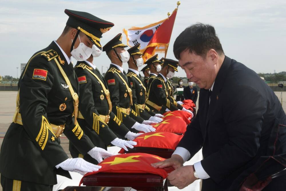 Chinese Ambassador to South Korea Xing Haiming (R) places his country's flag over caskets containing the remains of Chinese soldiers killed in the Korean War, during the handing over ceremony at South Korea's Incheon International Airport