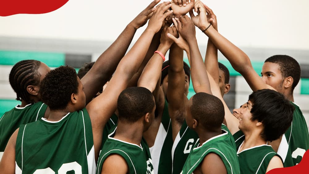 A basketball team with arms raised in huddle