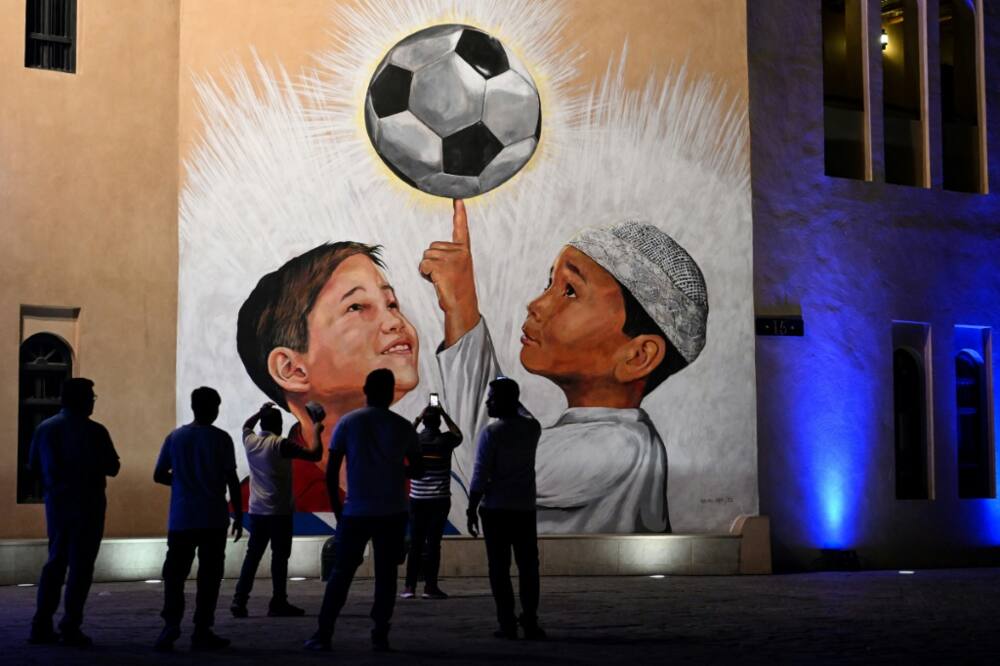 People look at a mural in Doha on November 4, 2022, ahead of the Qatar 2022 FIFA World Cup football tournament.