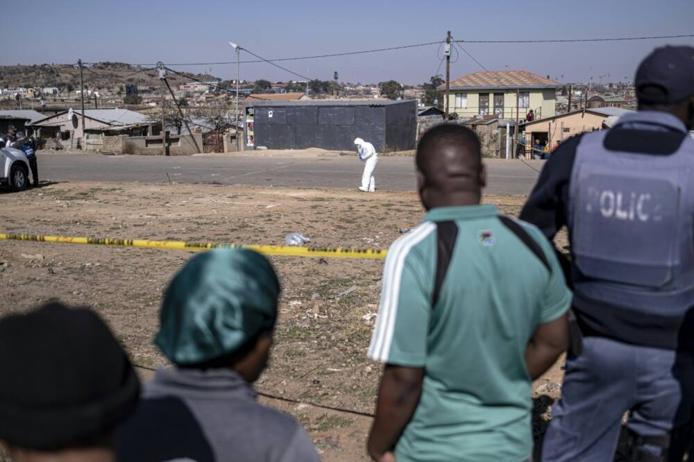 A forensic expert  inspects the crime scene where 15 people were killed in a Soweto bar