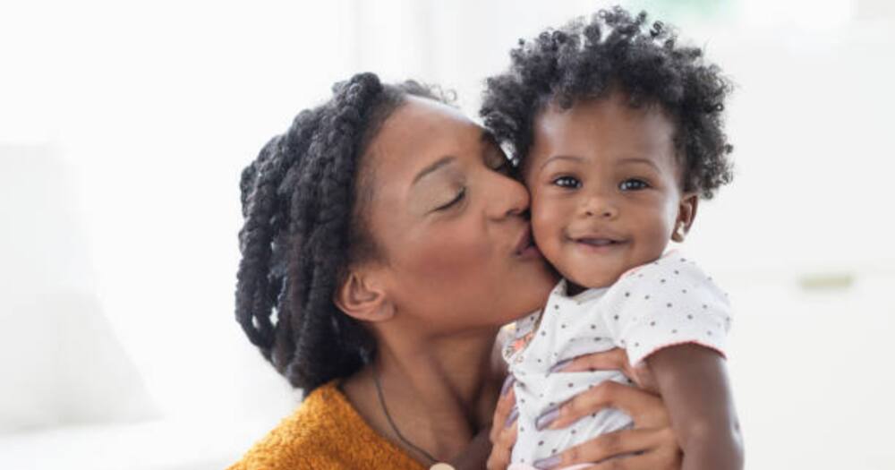 Black mum kissing daughter on cheek. Photo for illustration.