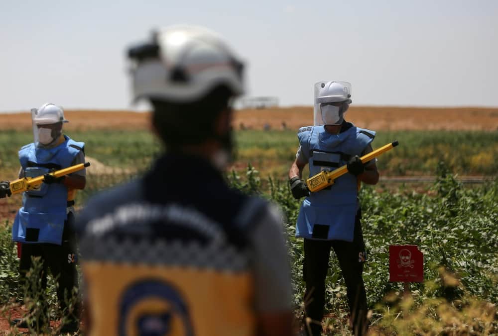 Members of the White Helmets get ready to search for and neutralise unexploded weapons in a field on the outskirts of al-Jinah village