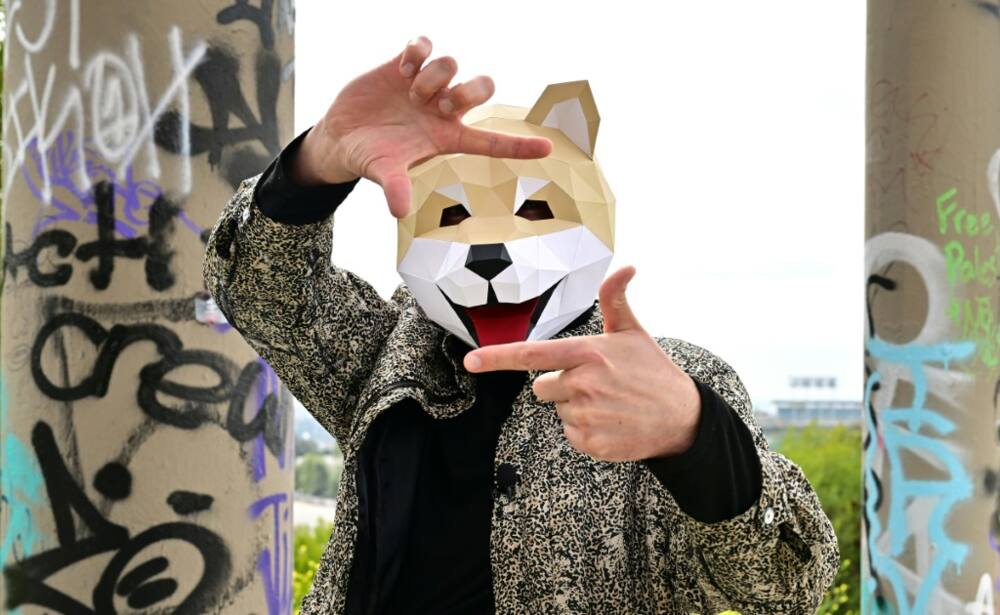 Tridog, a member of Own the Doge, wears a Doge mask as he poses for photos during an interview in Los Angeles