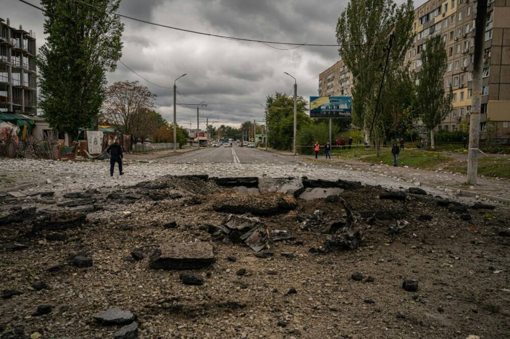 A policeman walks next to a crater following a missile strike in Dnipro