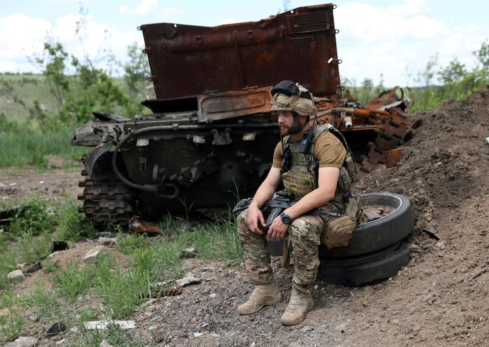 A Ukrainian serviceman sits next to a destroyed Russian tank not far from Lysychansk on Friday