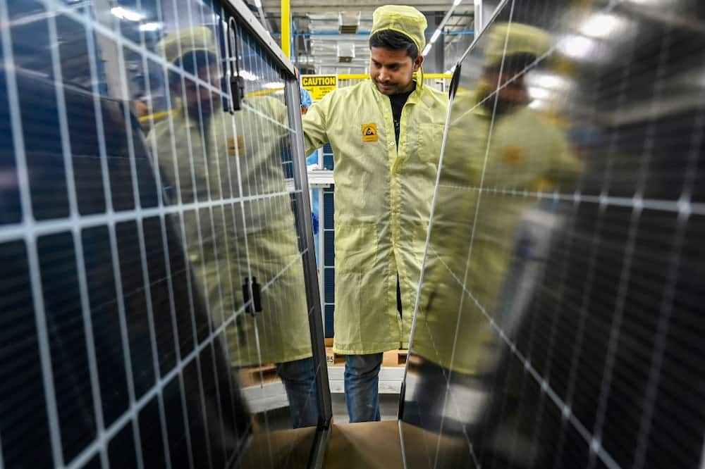 An employee inspects solar panels at an Adani Group factory in Mundra