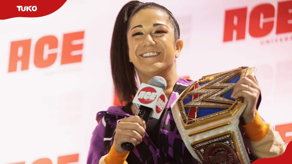 WWE's Bayley speaks onstage while holding the championship belt