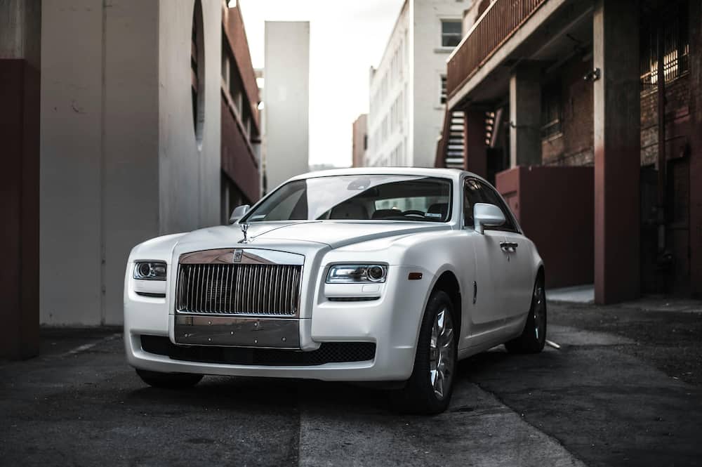 A white Rolls Royce is parked in an alley