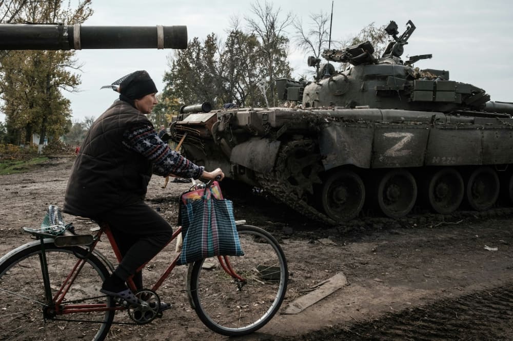 A local resident rides past an abandoned Russian tank marked Z near Kharkiv in Ukraine on September 30, 2022