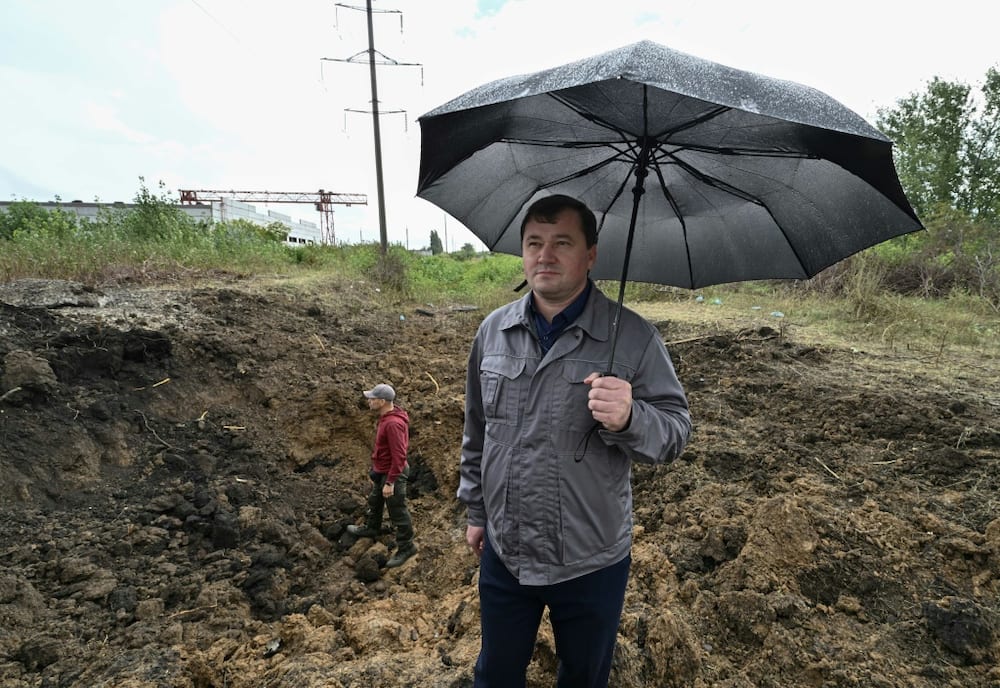 The head of plant Igor Polovich stands near a crater caused by the explosion