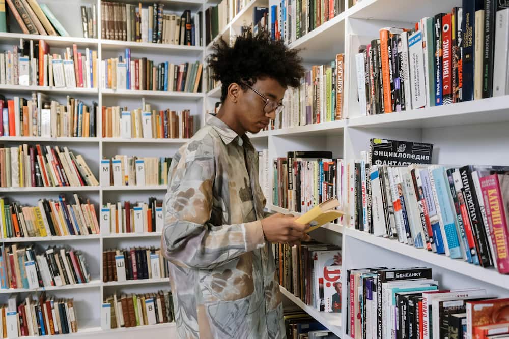 An afro-haired young man reading a book in the library