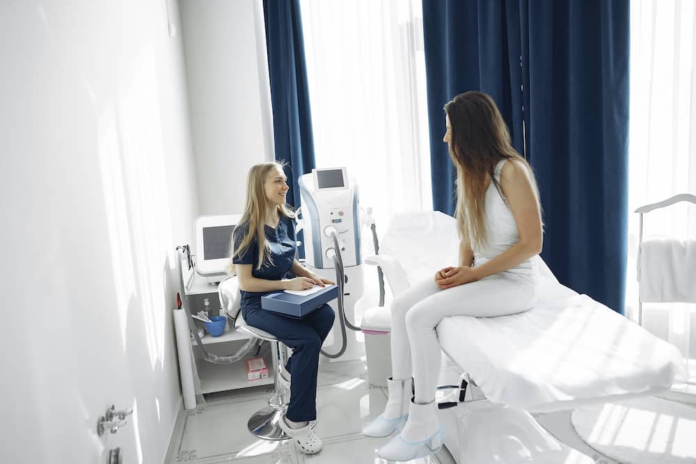 A nurse helps a patient sitting on a bed