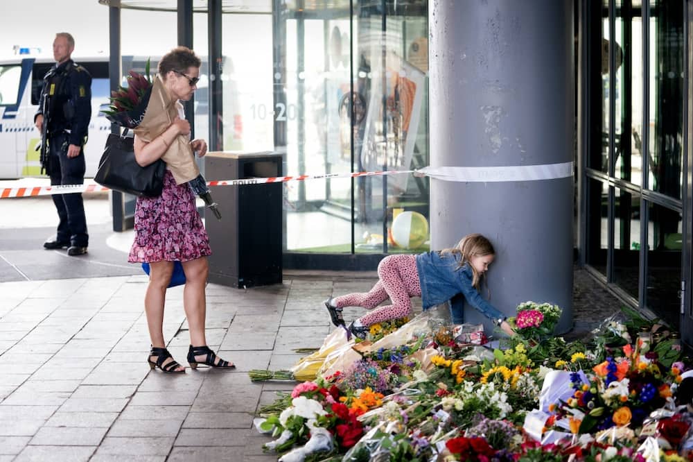 A girl places flowers at a makeshift memorial to the victims of the shooting in front of the Field's shopping centre