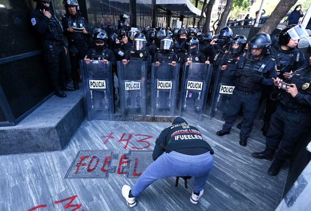 Protesters demanding justice for 43 Mexican students who disappeared in 2014 paint graffiti outside the attorney general's office in Mexico City