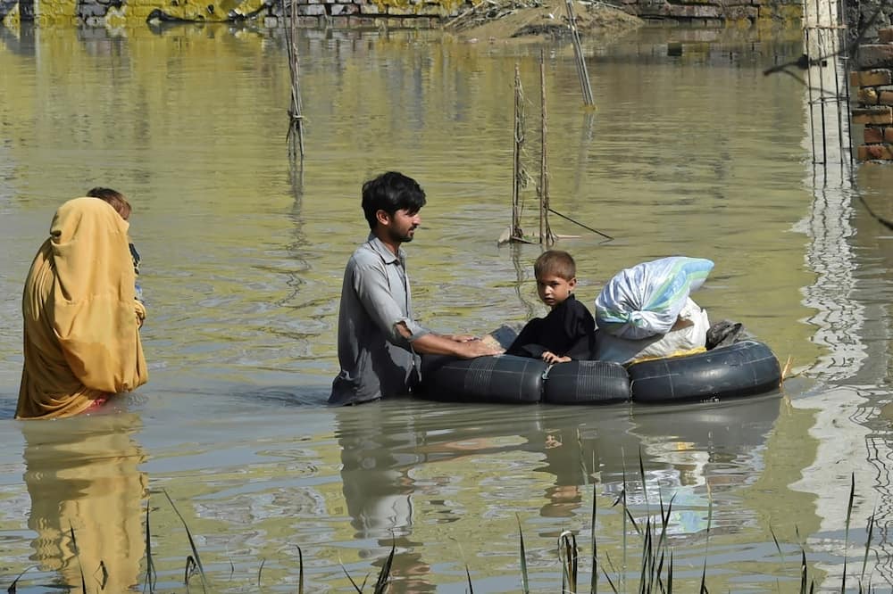 A family wades through a flood-hit area following heavy monsoon rains in Charsadda district of Khyber Pakhtunkhwa