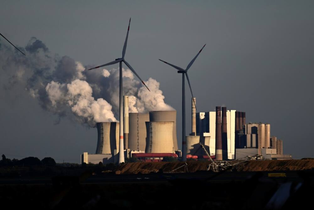 Wind turbines stand before a lignite-fired power plant near Niederaussem in western Germany