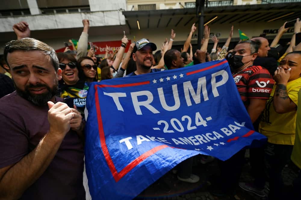 A supporter of Brazilian President Jair Bolsonaro, known as 'the Tropical Trump,' unfurls a pro-Trump flag at the president's re-election rally in Juiz da Fora, in Minas Gerias state in Brazil on August 16 2022