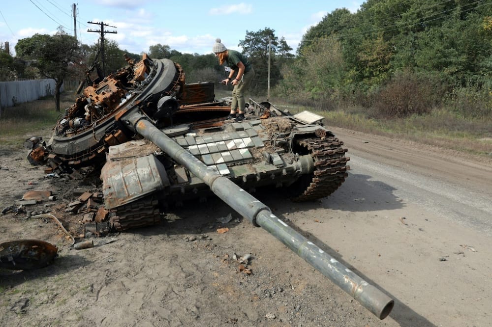 A girl inspects a destroyed Russian tank near the village of Oskol, Kharkiv region