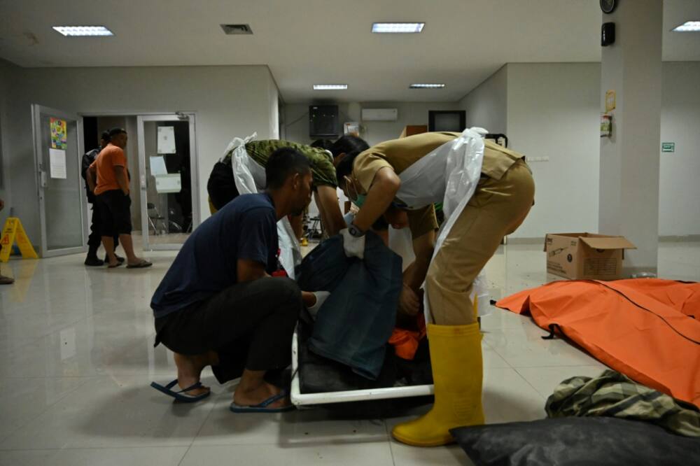 People handle a dead body following an earthquake, at a hospital in Cimacan