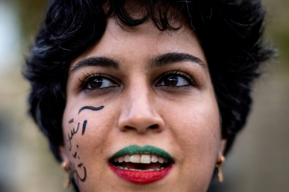 A woman wearing lipsticks in the colours of the Iranian flag takes part in a rally in support of protests in Iran in Paris