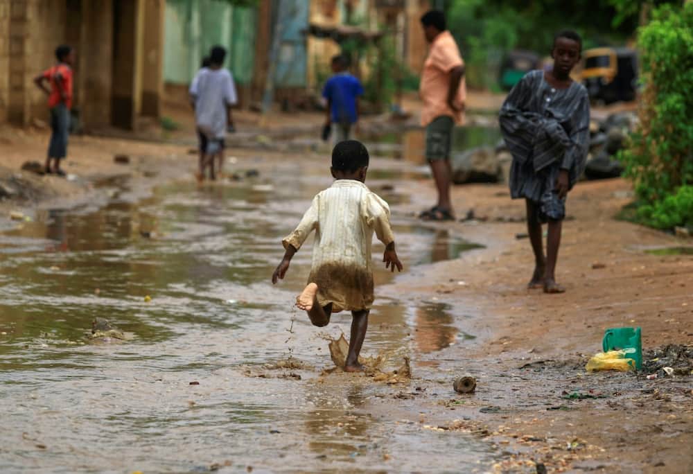 A boy runs through floodwater after a downpour in Sudan's capital Khartoum on August 13, 2022