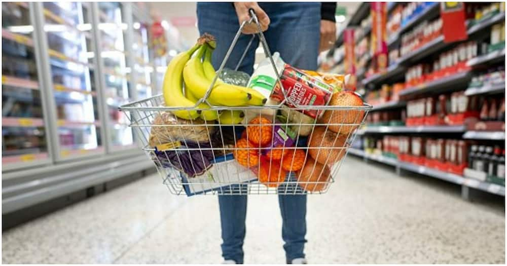 A customer holding a shopping basket with food items.