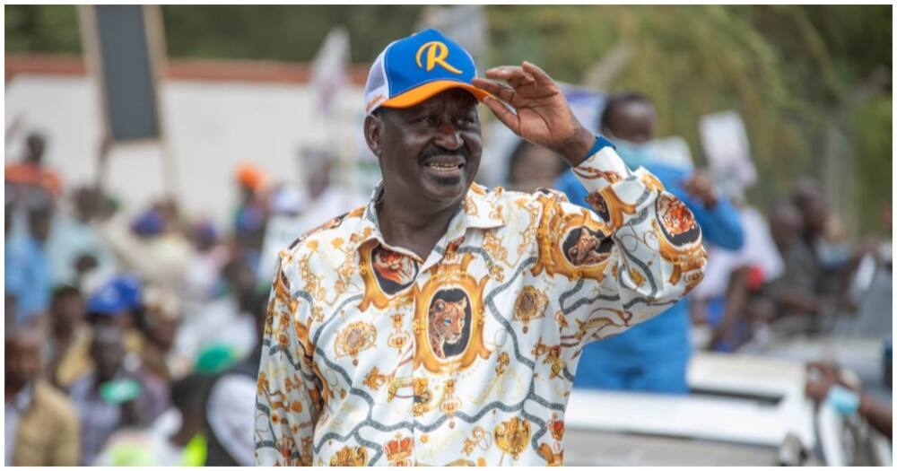 Man holds a cap while gesturing at a crowd.