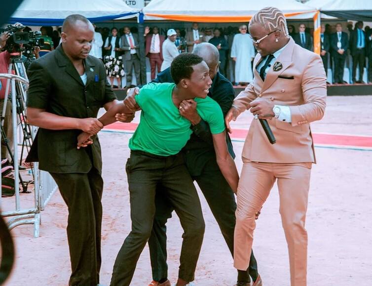 Excited fan hangs on TZ singer Harmonize's leg during performance for Magufuli